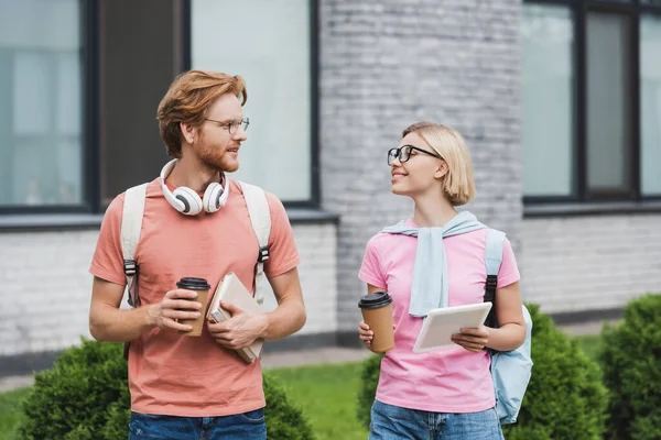Students in glasses holding coffee to go and looking at each other outside — Stock Photo