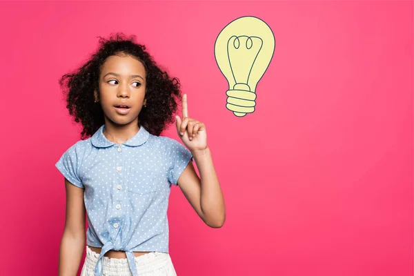 Frisé afro-américain gosse montrant geste idée près ampoule illustration sur rose — Photo de stock