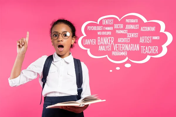 Shocked african american schoolgirl with book showing idea gesture near thought bubble with greeting lettering on pink — Stock Photo