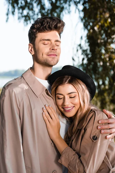 Mann mit geschlossenen Augen umarmt Frau mit Hut draußen — Stockfoto