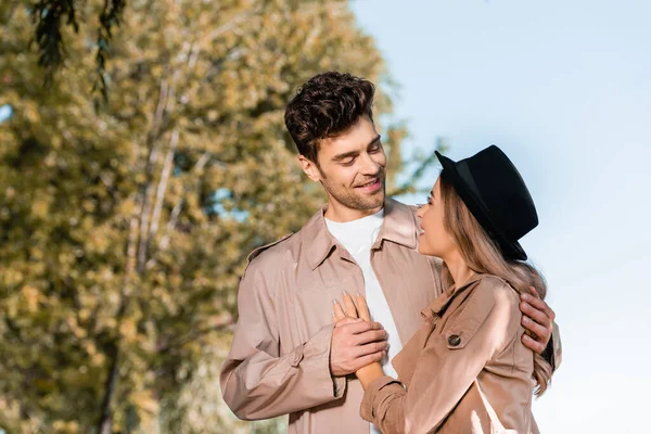 Hombre elegante tocando la mano de la mujer en el sombrero exterior - foto de stock