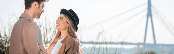 Panoramic shot of woman in hat and man looking at each other outside — Stock Photo