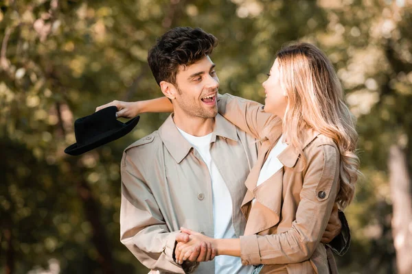 Pareja emocionada tomados de la mano y mirándose unos a otros en el parque otoñal - foto de stock