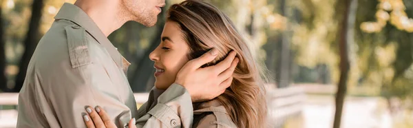 Panoramic shot of man touching hair of woman with closed eyes outside — Stock Photo