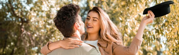 Aufgeregte Frau mit Hut umarmt Freund im herbstlichen Park, Panoramaaufnahme — Stockfoto