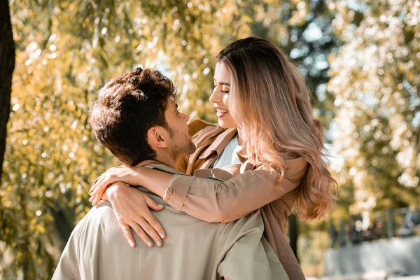 Femme étreignant et regardant petit ami dans le parc automnal — Photo de stock