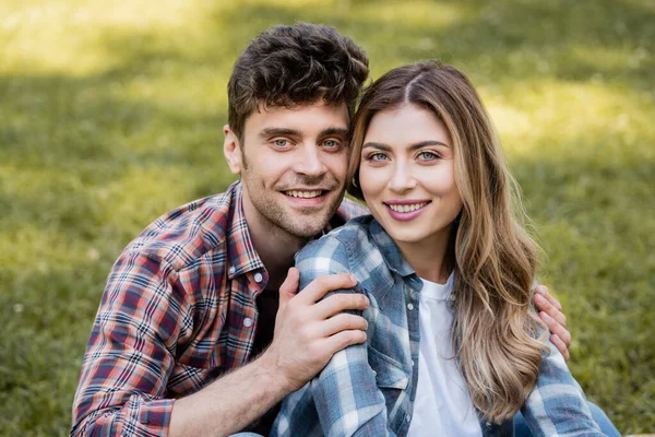 Homme toucher femme et regarder la caméra dans le parc — Photo de stock