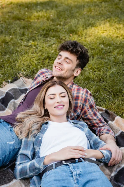 Man and woman in plaid shirts lying on blanket — Stock Photo