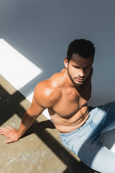 High angle view of shirtless man sitting on white — Stock Photo