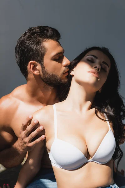 Shirtless man touching seductive woman in bra isolated on grey — Stock Photo