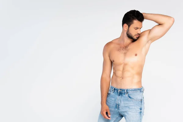 Мужчина без рубашки в джинсах позирует и смотрит в сторону, изолированный от белого — стоковое фото