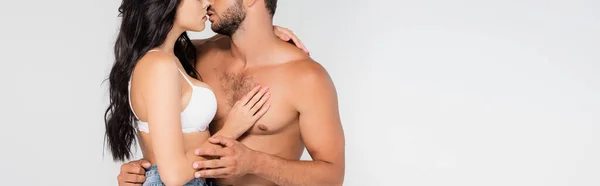 Панорамный урожай сексуальной женщины, касающейся и целующей мужчину без рубашки, изолированного на сером — стоковое фото