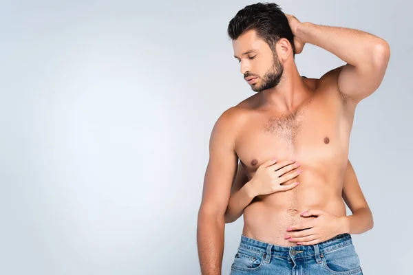 Mulher tocando o tronco do homem muscular isolado no cinza — Fotografia de Stock