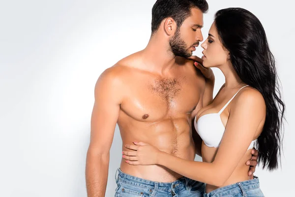 Side view of shirtless man hugging brunette woman in bra on white — Stock Photo