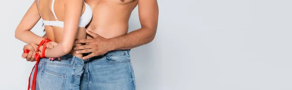 Cultivo horizontal de mujer sumisa con las manos atadas cerca del hombre musculoso aislado en blanco - foto de stock