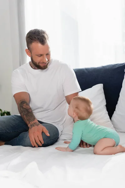 Enfoque selectivo de padre y bebé niño mirándose en el dormitorio - foto de stock