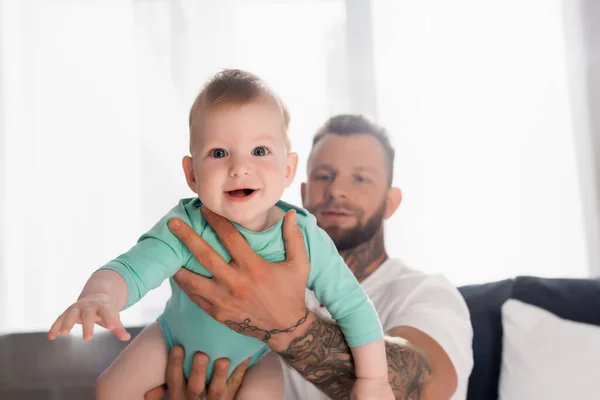 Foyer sélectif de bébé garçon excité dans les mains du jeune père dans la chambre — Photo de stock
