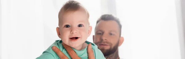 Encabezado del sitio web de padre joven sosteniendo niño bebé mirando a la cámara con la boca abierta - foto de stock