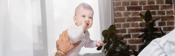 Concept horizontal de bébé garçon excité tenant la main dans la bouche tout en regardant loin — Photo de stock