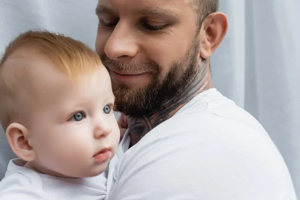 Selective focus of joyful bearded man holding infant son in hands — Stock Photo