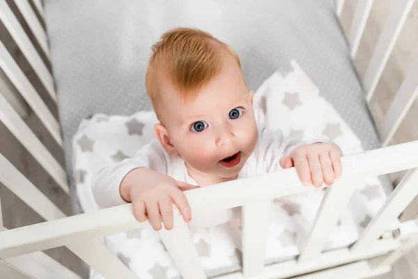 Над головой вид младенца, смотрящего в камеру, стоя в кроватке — стоковое фото