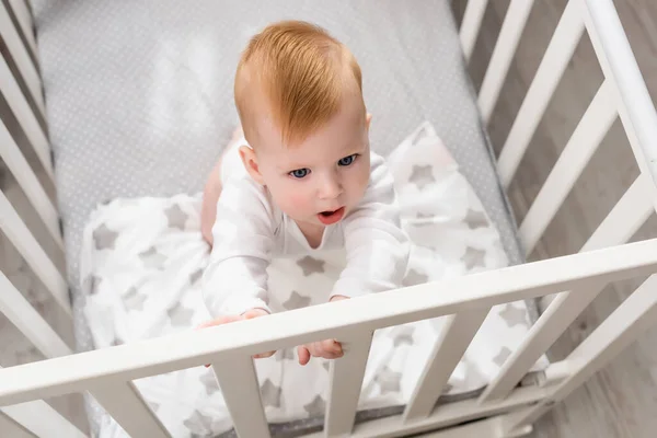 Overhead view of infant boy standing in crib — Stock Photo