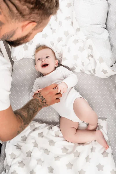 Foyer sélectif de jeune père touchant bébé garçon excité couché dans la crèche — Photo de stock