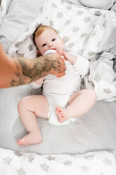 Foco seletivo do homem tatuado alimentando o filho bebê de mamadeira — Fotografia de Stock