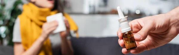 Cropped view of man holding nasal spray and woman sneezing on background, website header — Stock Photo