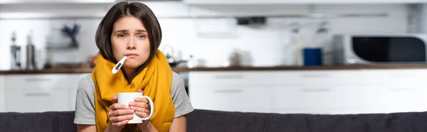 Concetto orizzontale di donna malata con termometro in bocca contenente tazza di bevanda riscaldante — Foto stock