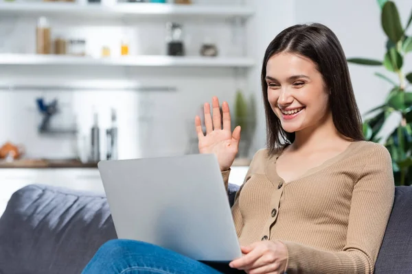 Excited freelancer waving hand during video chat on laptop in kitchen — Stock Photo