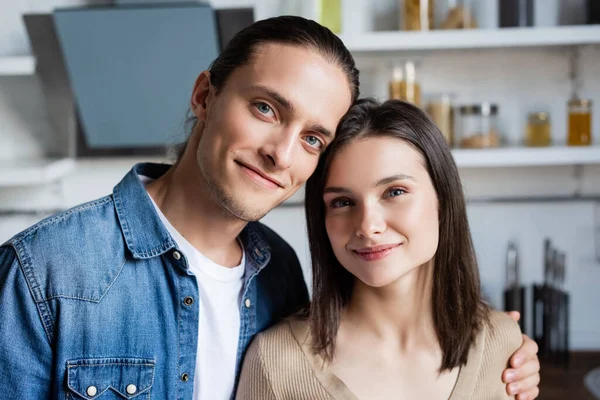 Freudiges Paar blickt in die Kamera, während es gemeinsam in der Küche steht — Stockfoto