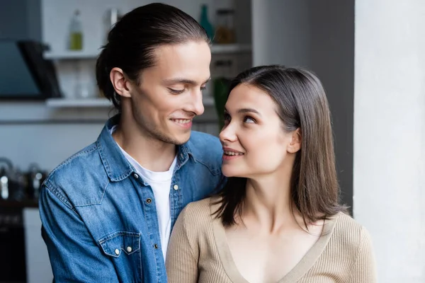 Junges Paar schaut einander an, während sie zu Hause zusammen stehen — Stockfoto