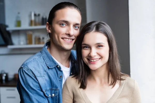 Freudiges Paar blickt in die Kamera, während es gemeinsam in der Küche steht — Stockfoto