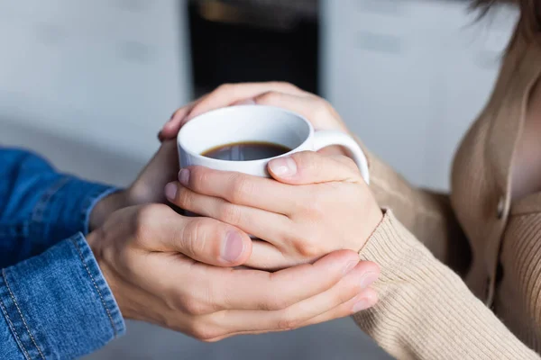 Cropped view of man and woman holding cup of coffee together — Stock Photo