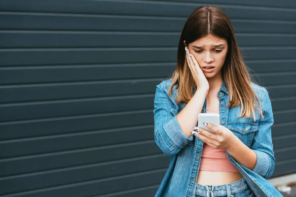 Besorgter Teenager nutzt Smartphone in der Nähe von Gebäuden — Stockfoto