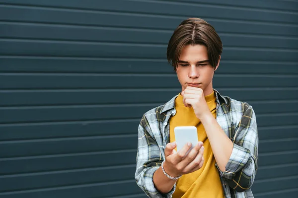 Adolescente pensativo usando smartphone perto de construção ao ar livre — Fotografia de Stock