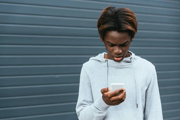 Adolescente afro-americano perturbado usando smartphone ao ar livre — Fotografia de Stock