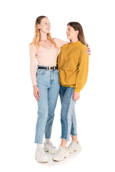 Lächelnde Teenager, die einander auf weißem Hintergrund umarmen und anschauen — Stockfoto