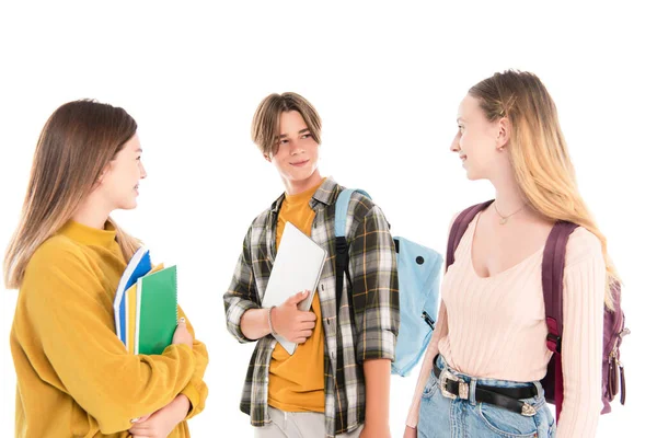 Teenagers with backpacks and notebooks smiling at each other isolated on white — Stock Photo