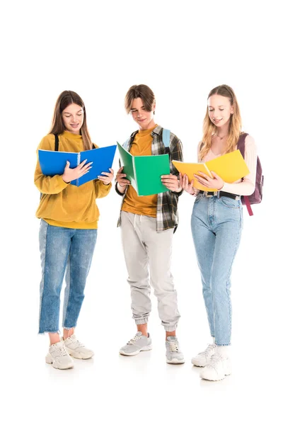 Smiling teenagers with backpacks looking at copy books on white background — Stock Photo
