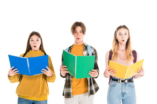 Aufgeregte Teenager blicken in die Kamera, während sie ihre Notizbücher isoliert auf weiß halten — Stockfoto