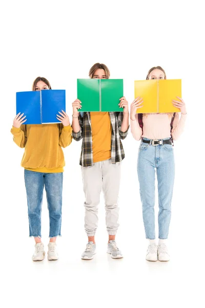 Adolescentes cobrindo rostos com cadernos sobre fundo branco — Fotografia de Stock