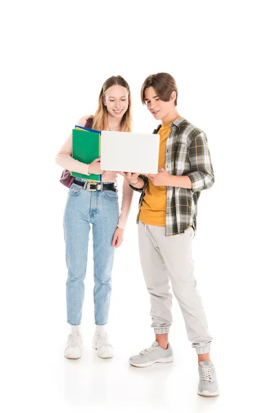 Adolescente menino segurando laptop perto de amigo com cadernos no fundo branco — Fotografia de Stock