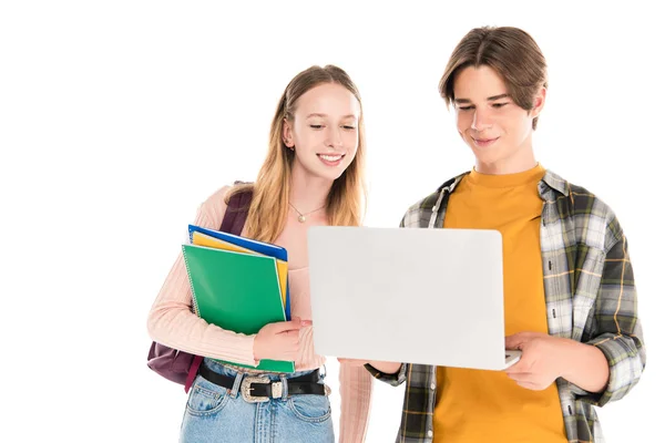 Adolescents souriants avec cahiers à l'aide d'un ordinateur portable isolé sur blanc — Photo de stock
