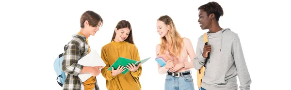 Horizontal crop of smiling multicultural teenagers with laptop, notebook and backpacks isolated on white — Stock Photo