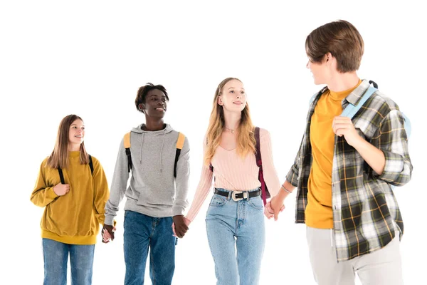 Sonrientes adolescentes multiétnicos tomados de las manos aislados en blanco - foto de stock