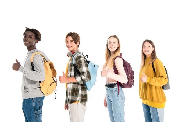 Multicultural teen friends with backpacks showing like and smiling at camera isolated on white — Stock Photo