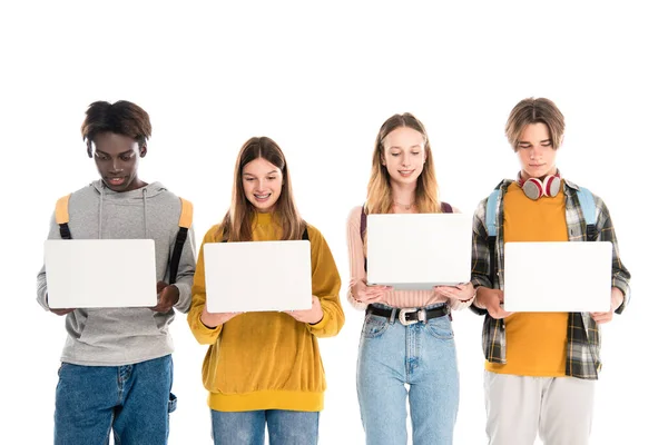 Positive multicultural teenagers holding laptops isolated on white — Stock Photo