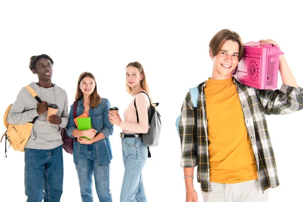 Smiling teenager holding boombox near multiethnic friends with coffee to go and books isolated on white — Stock Photo
